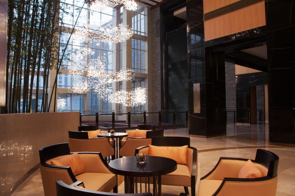Lobby d'hôtel haut de gamme avec espaces lounge et luminaires décoratifs.