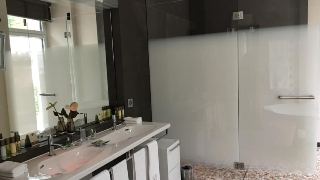 Salle de bains d’hôtel haut de gamme avec douche, illustrant l’équilibre entre confort et sobriété hydrique