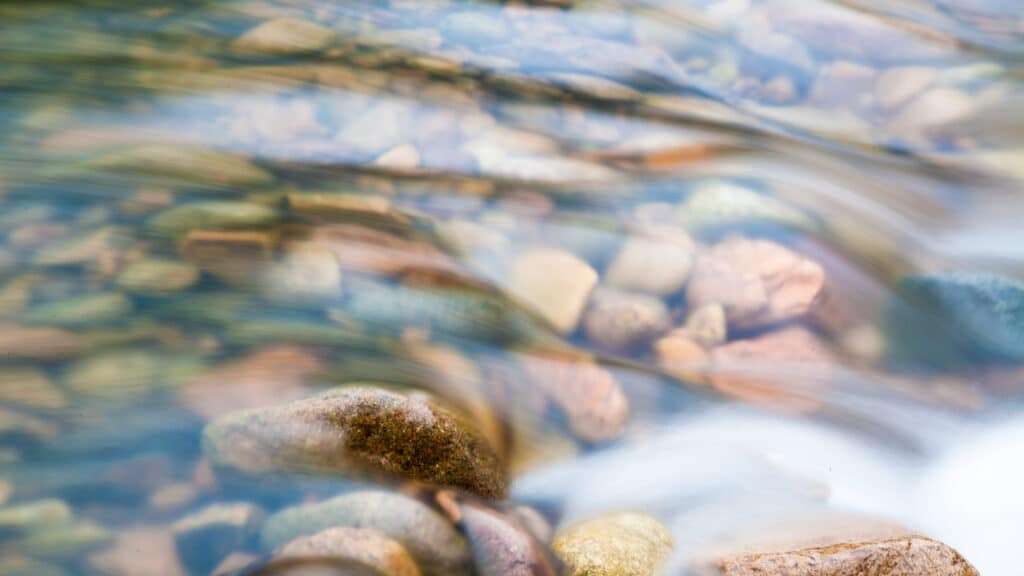 Écoulement d’eau sur des galets illustrant le cycle de l’eau et la gestion de la ressource à l’échelle du territoire
